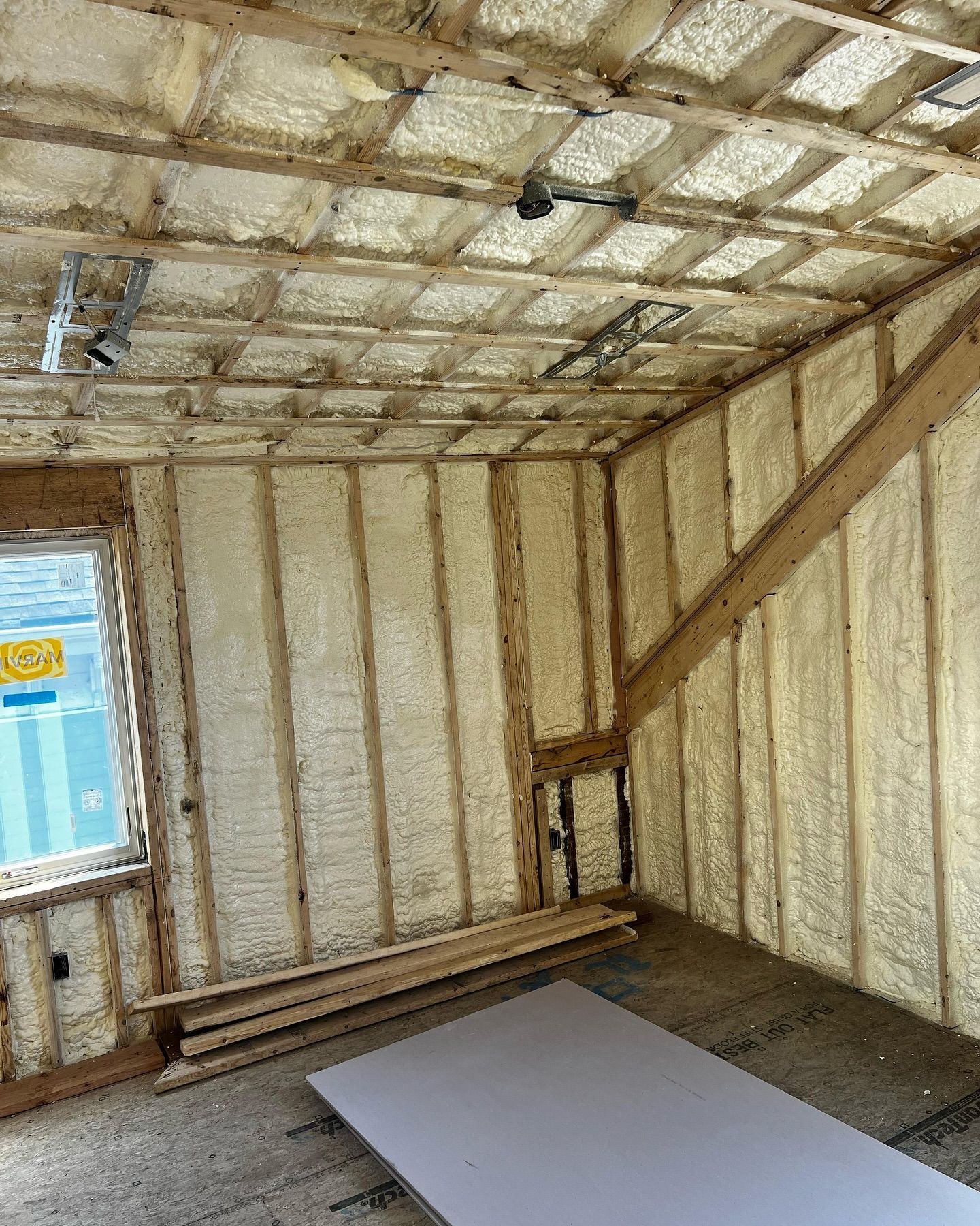 Interior framing with spray foam insulation on walls and ceiling, construction in progress.