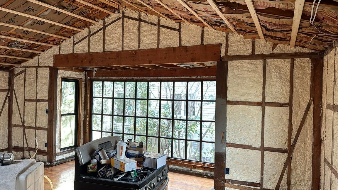Interior of a building under construction, showing exposed wooden framing with spray foam insulation.