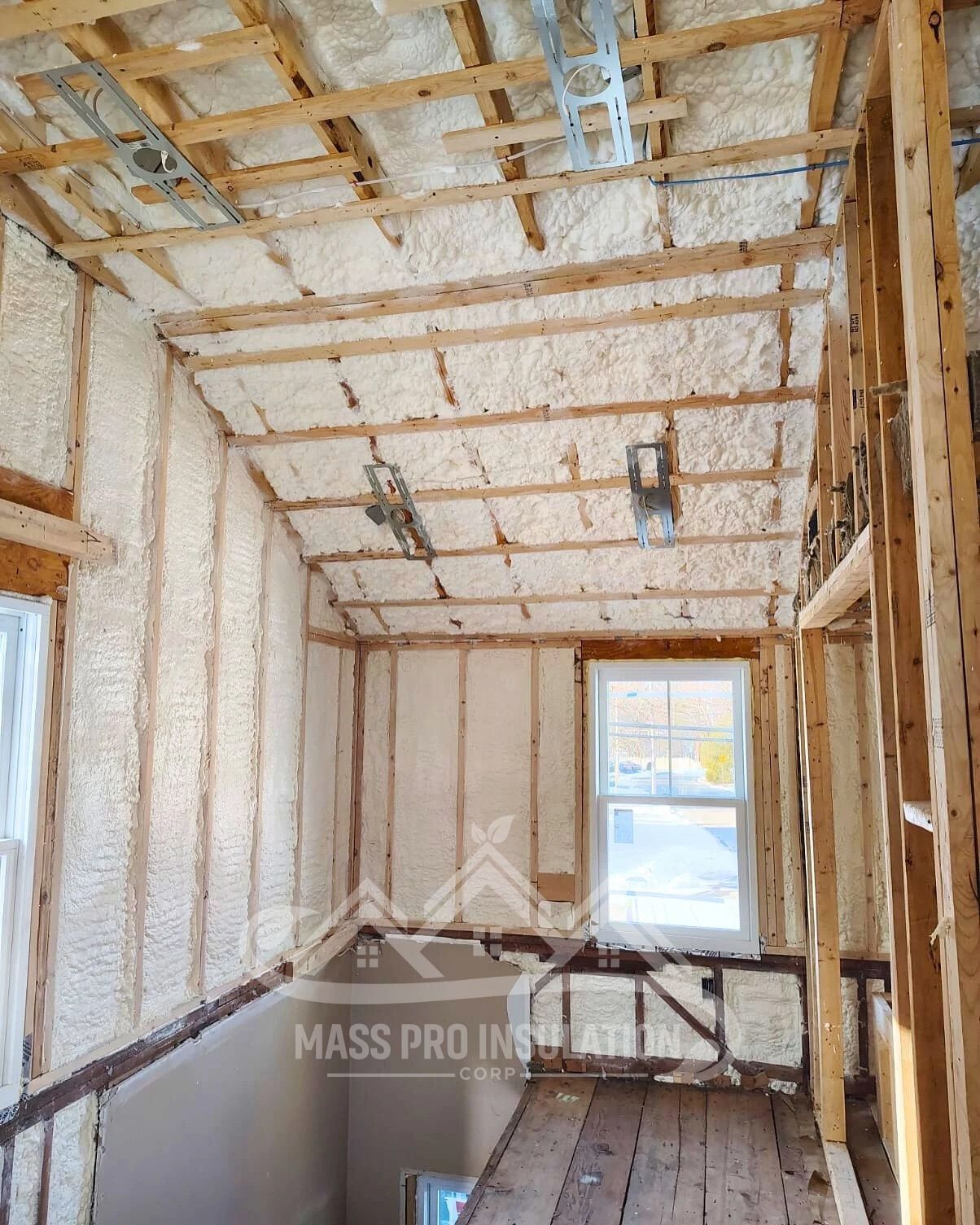 Spray foam insulation applied to walls and ceiling of a room under construction.