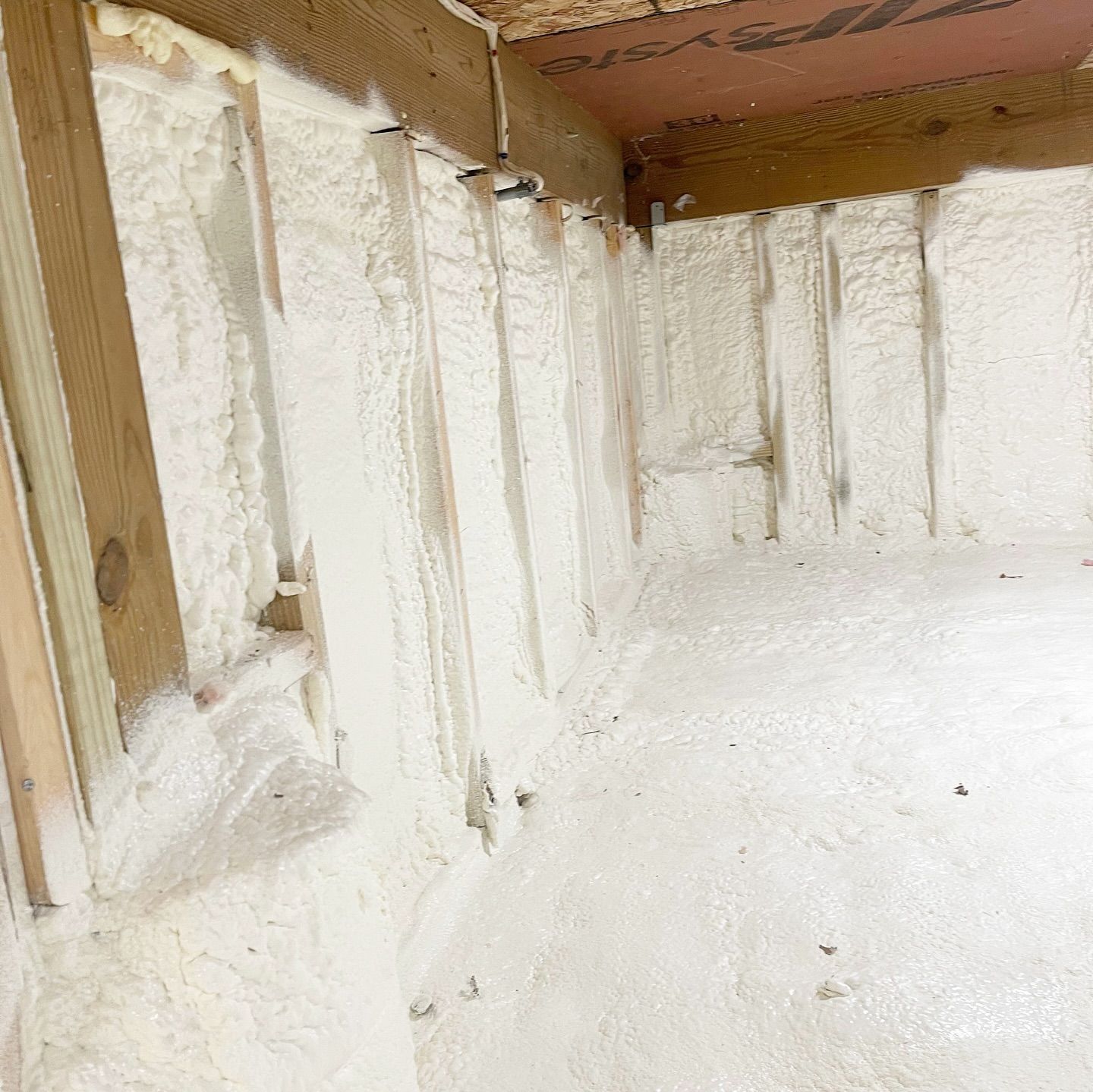 Interior wall framing covered in thick, white spray foam insulation.