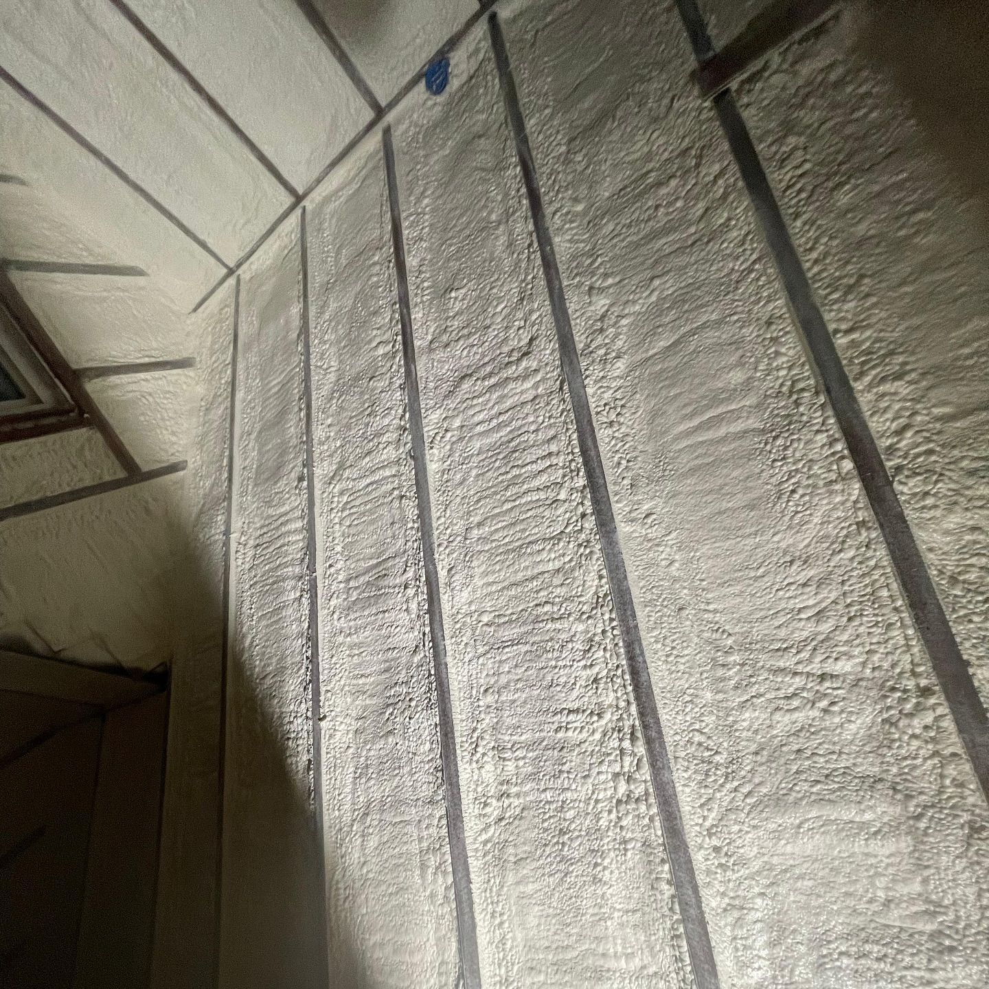 Spray foam insulation applied to interior walls and ceiling of a room.