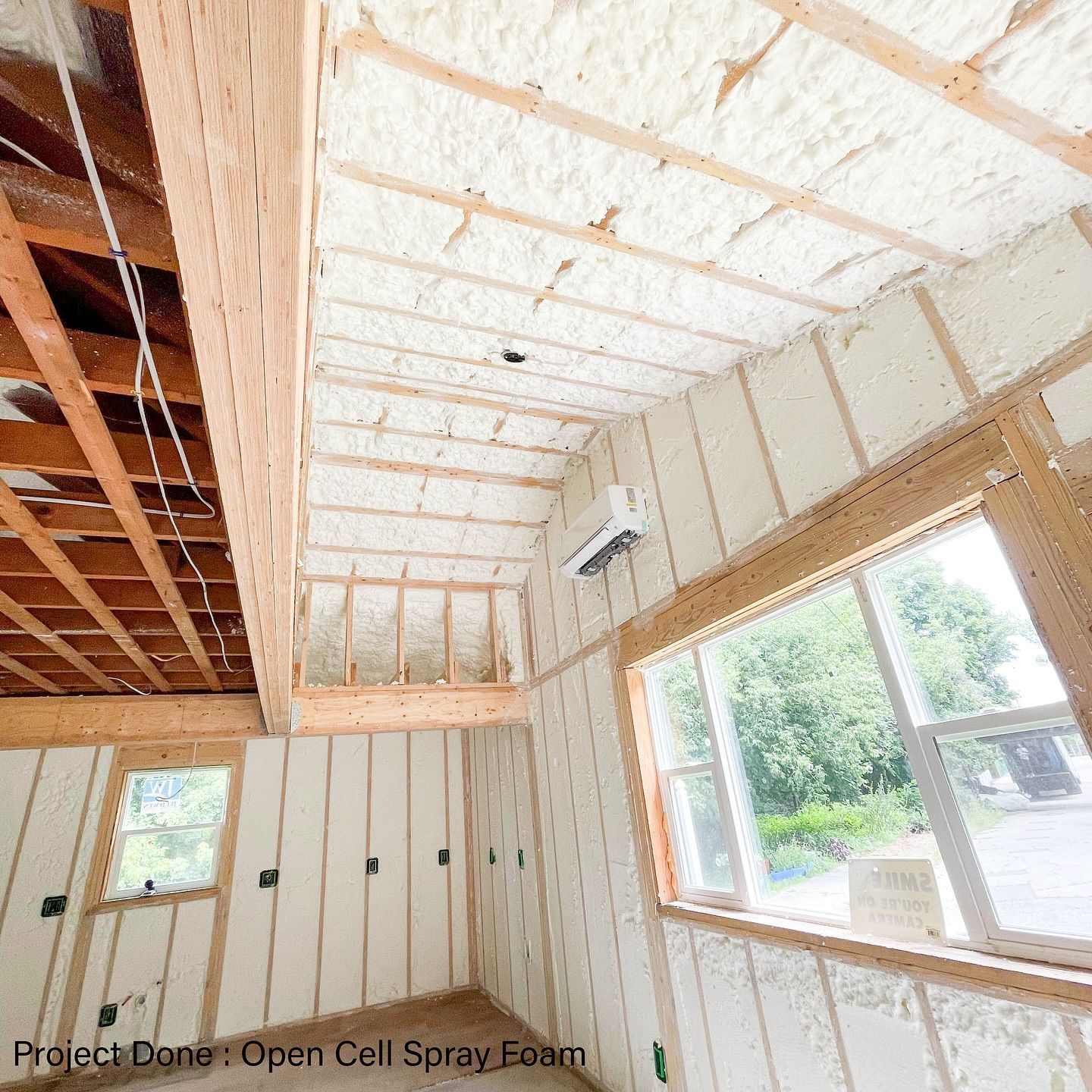 Interior view of a room being insulated with open-cell spray foam insulation on walls and ceiling.