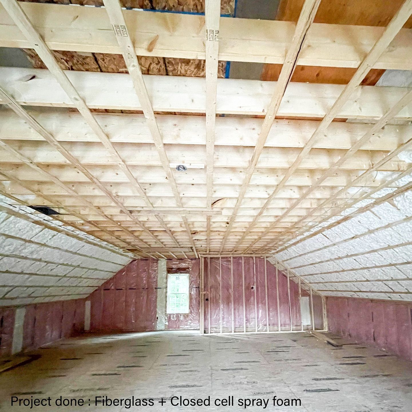 Interior of a room under construction. Wooden beams and pink insulation are visible.