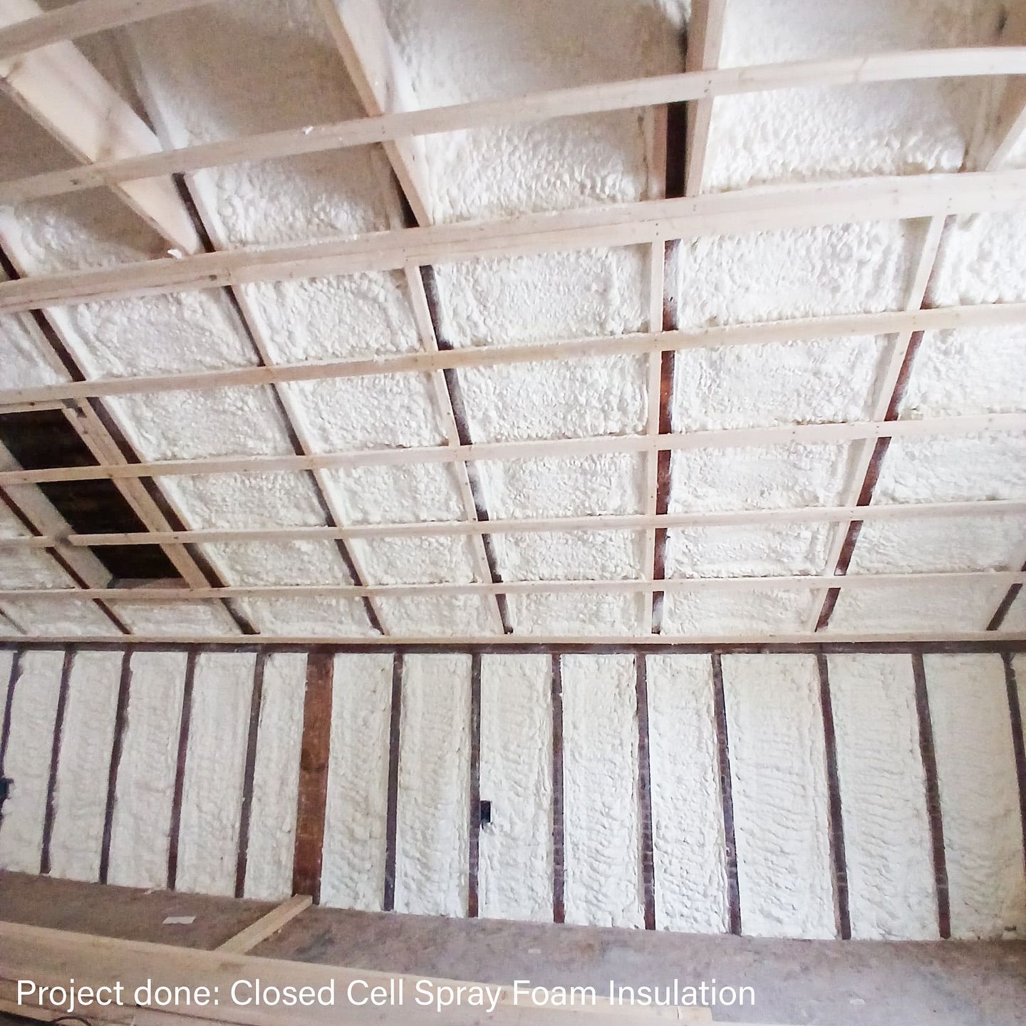 Spray foam insulation applied to ceiling and wall studs in a building.