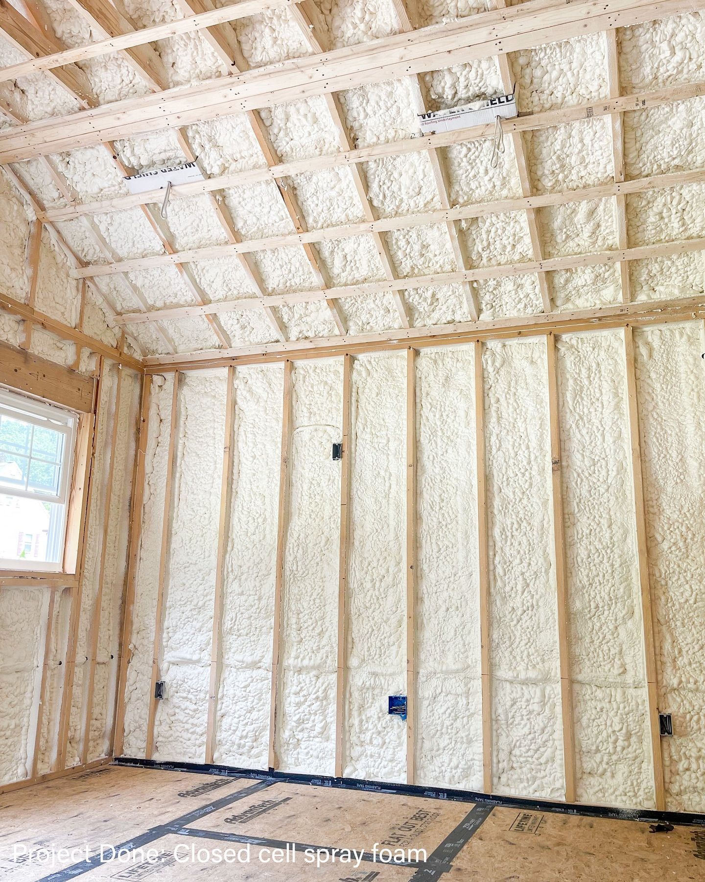 Interior of a building under construction. Walls and ceiling are covered in white spray foam insulation.