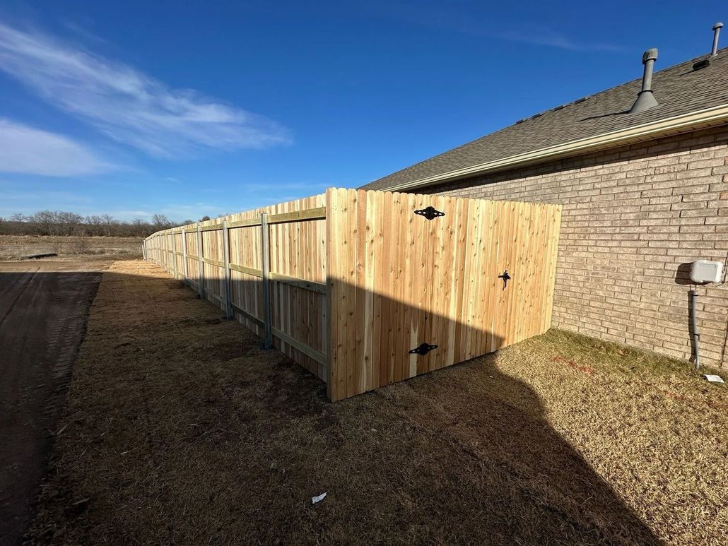 Person painting a wooden fence with green paint.