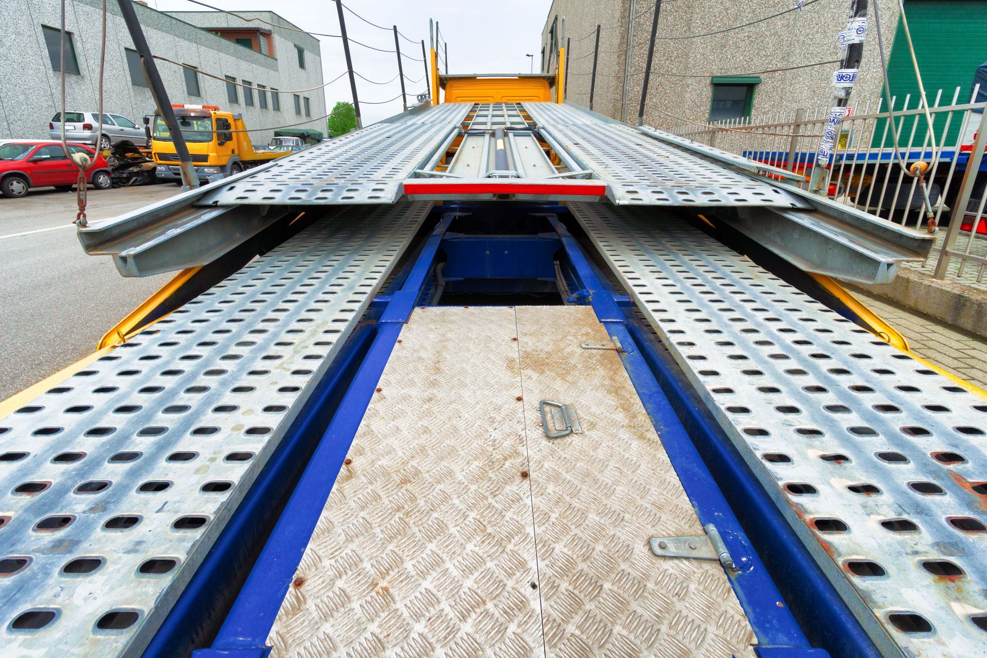 Empty car carrier bed, yellow and blue metal, viewed from rear.