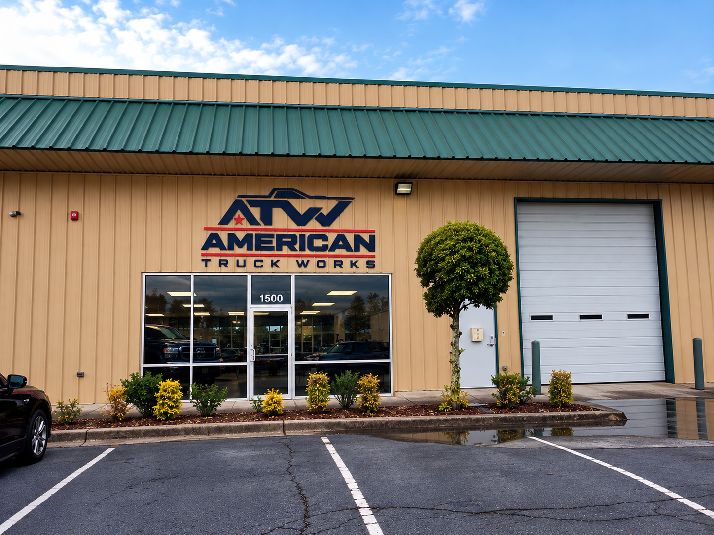 American Truck Works storefront with tan siding, green roof, and parking lot