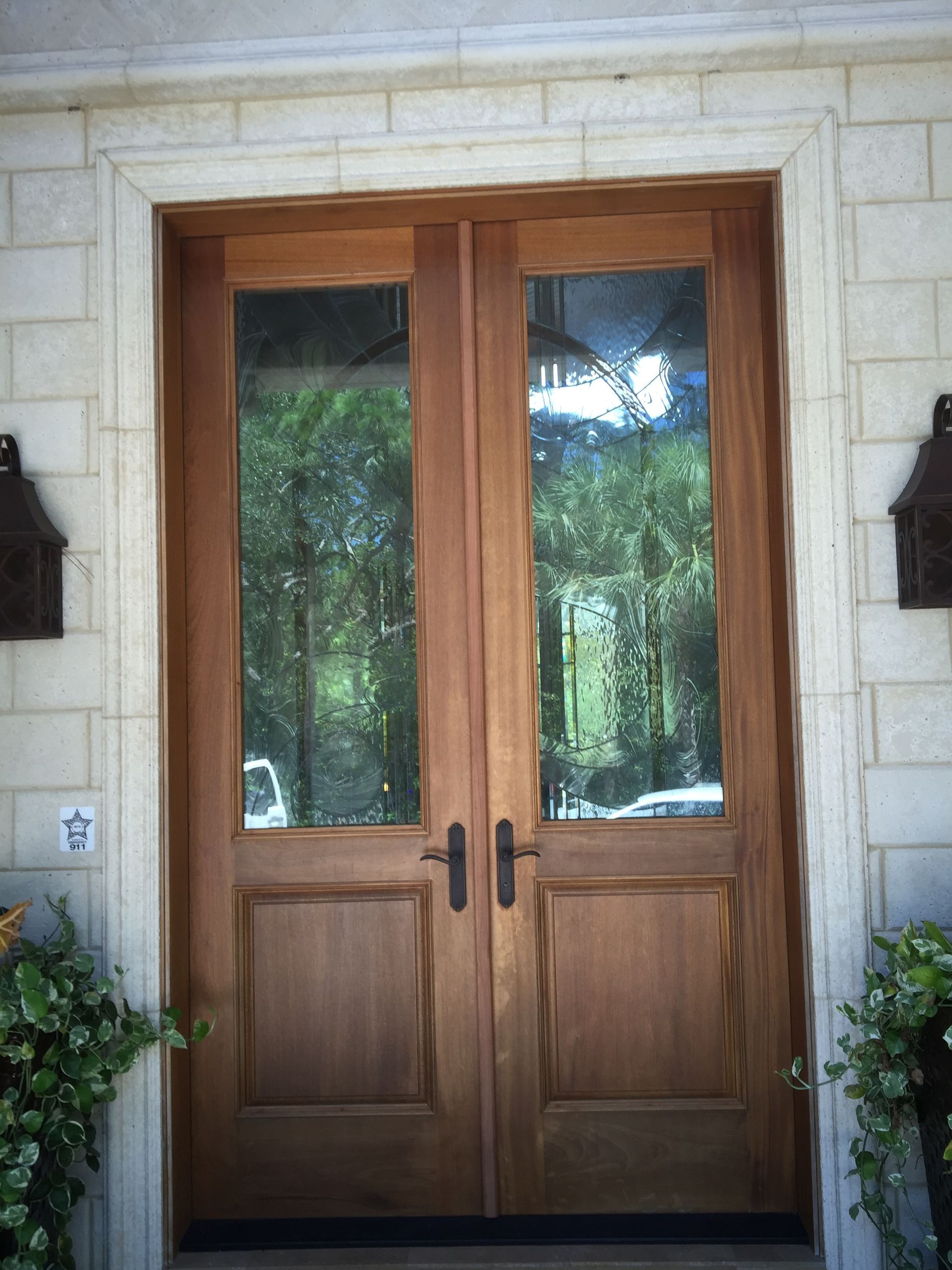Wooden double front doors with glass panes set in a stone exterior wall