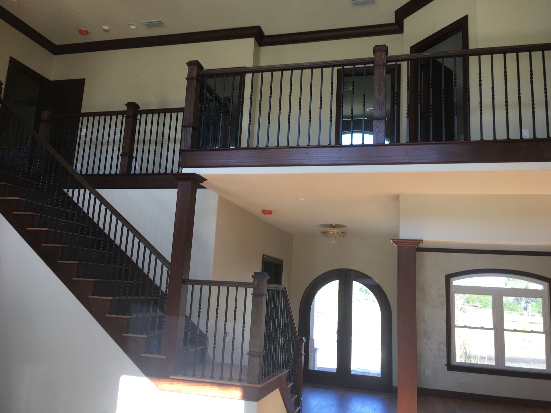 Interior with staircase, upper balcony railings, and arched windows in a two-story home