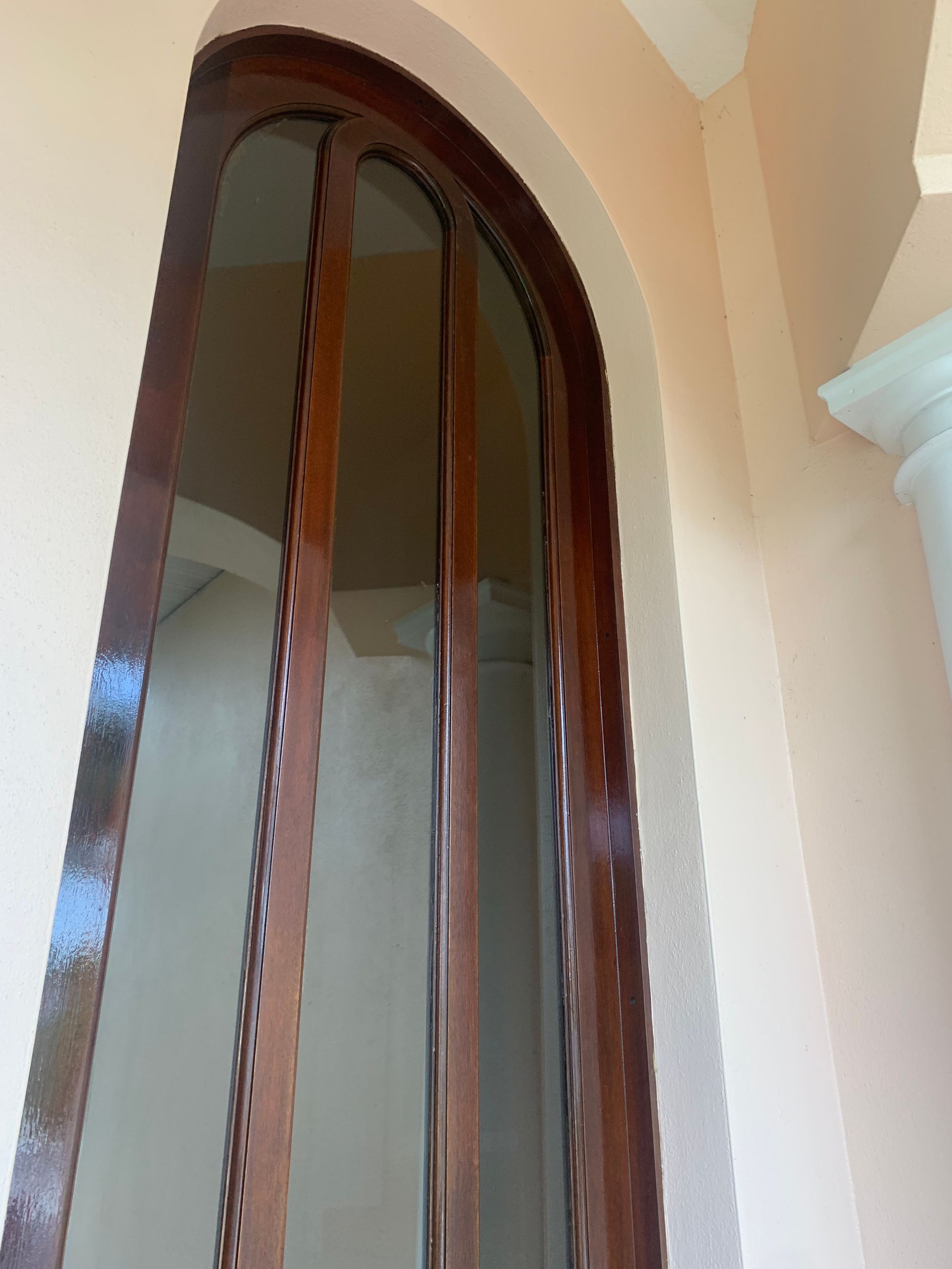 Arched wooden-framed glass door in a beige interior wall
