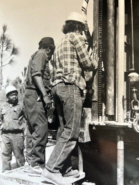 A black and white photo of a group of men working on a machine.