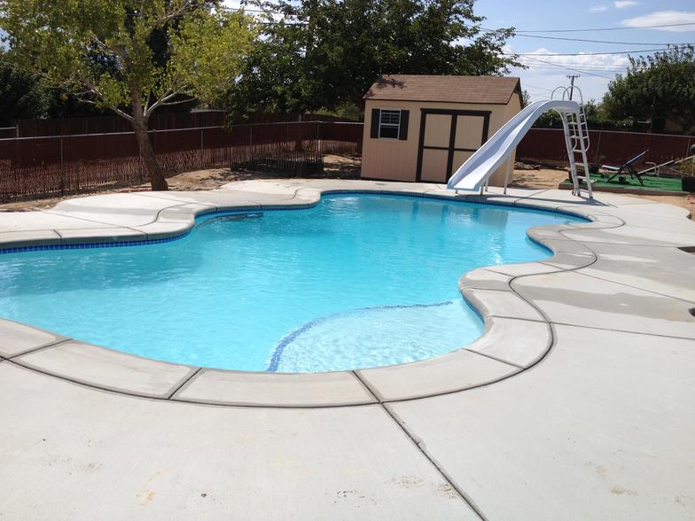 A large swimming pool with a slide and a shed in the background