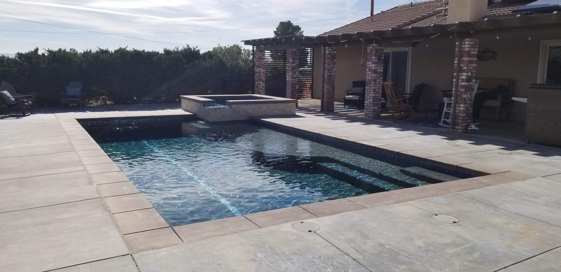 There is a large swimming pool in the backyard of a house.