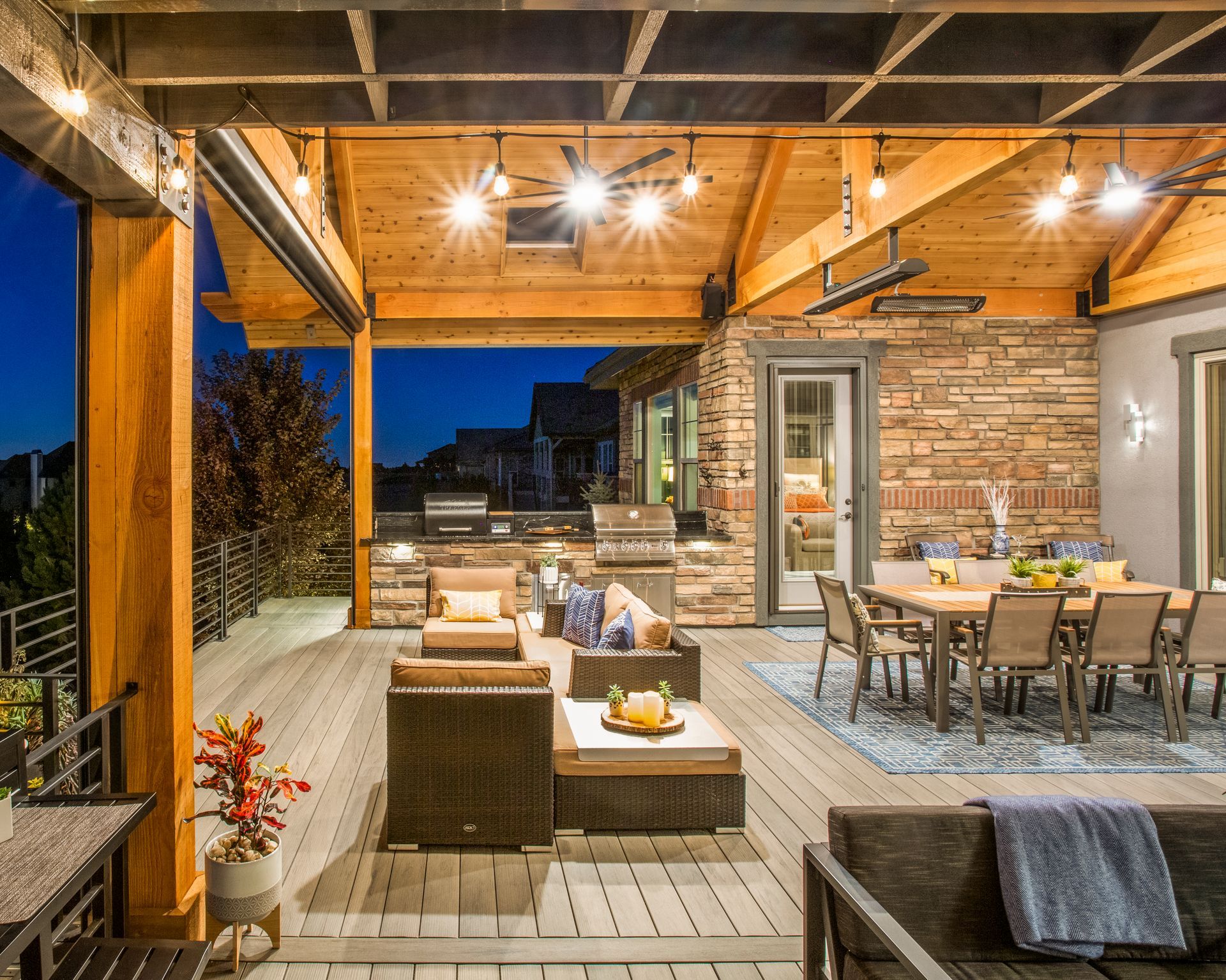 a large covered patio with a dining table, chairs, and a grill
