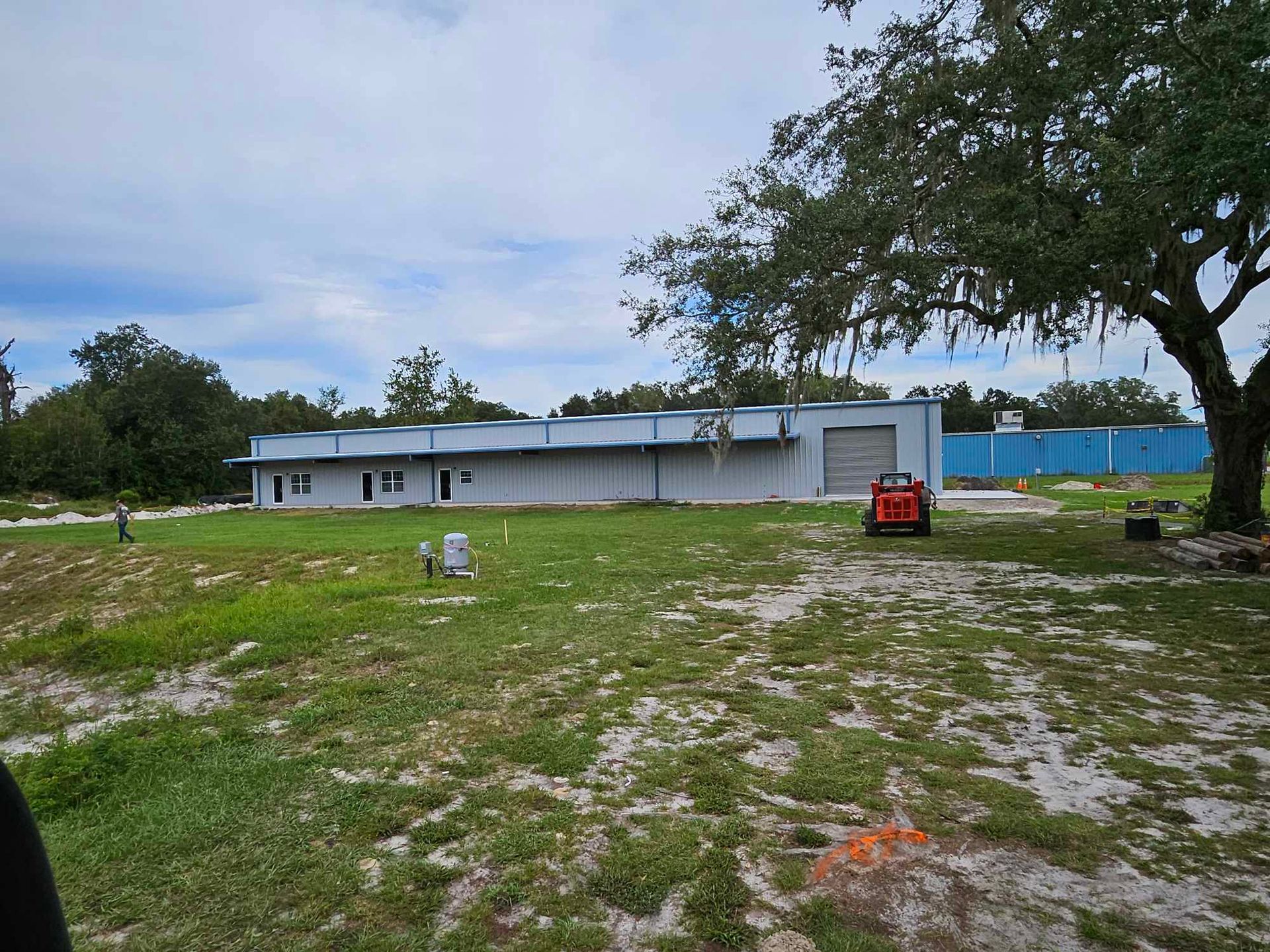 A large white building is sitting in the middle of a grassy field