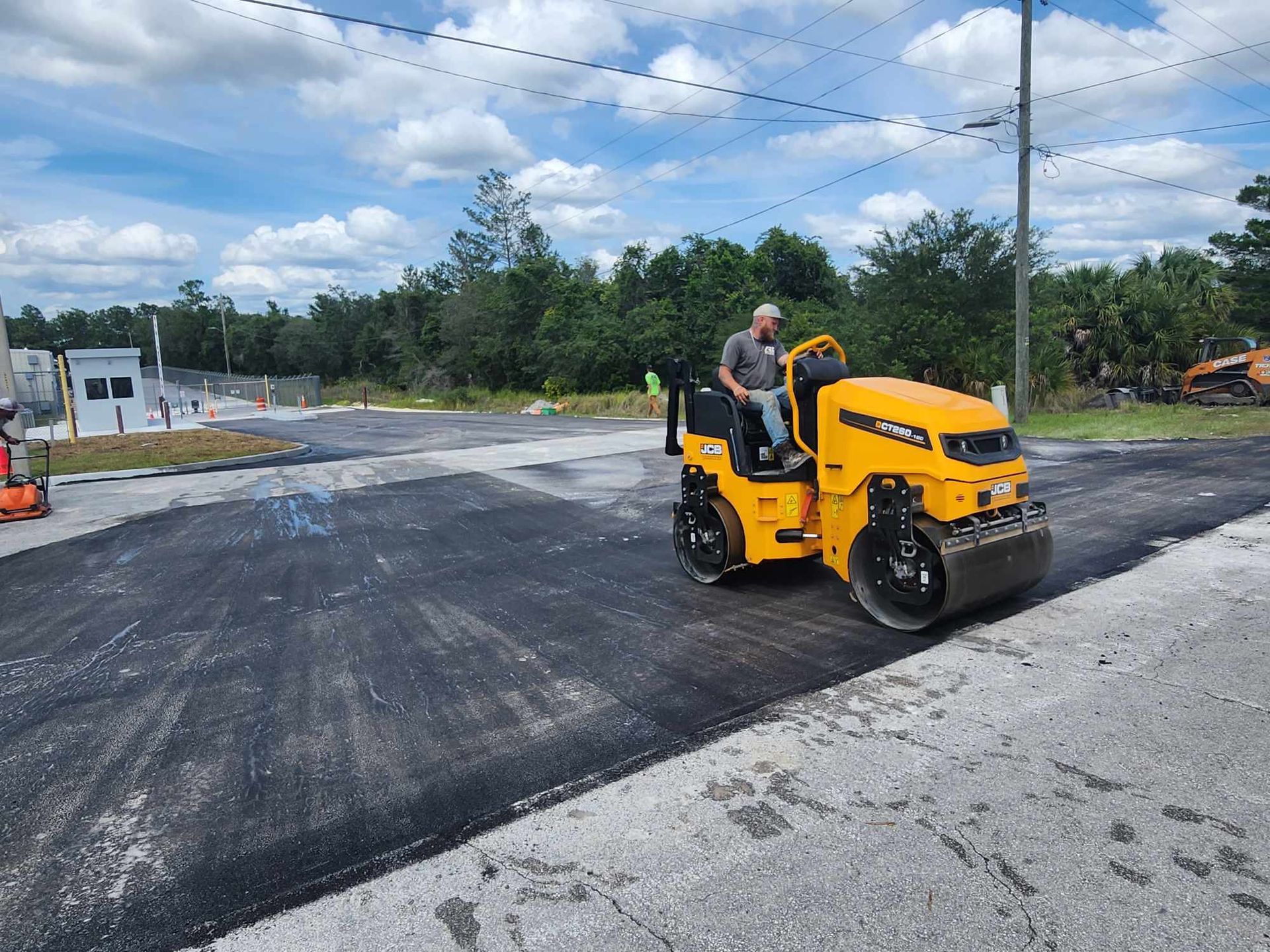 A man is driving a yellow roller on a road