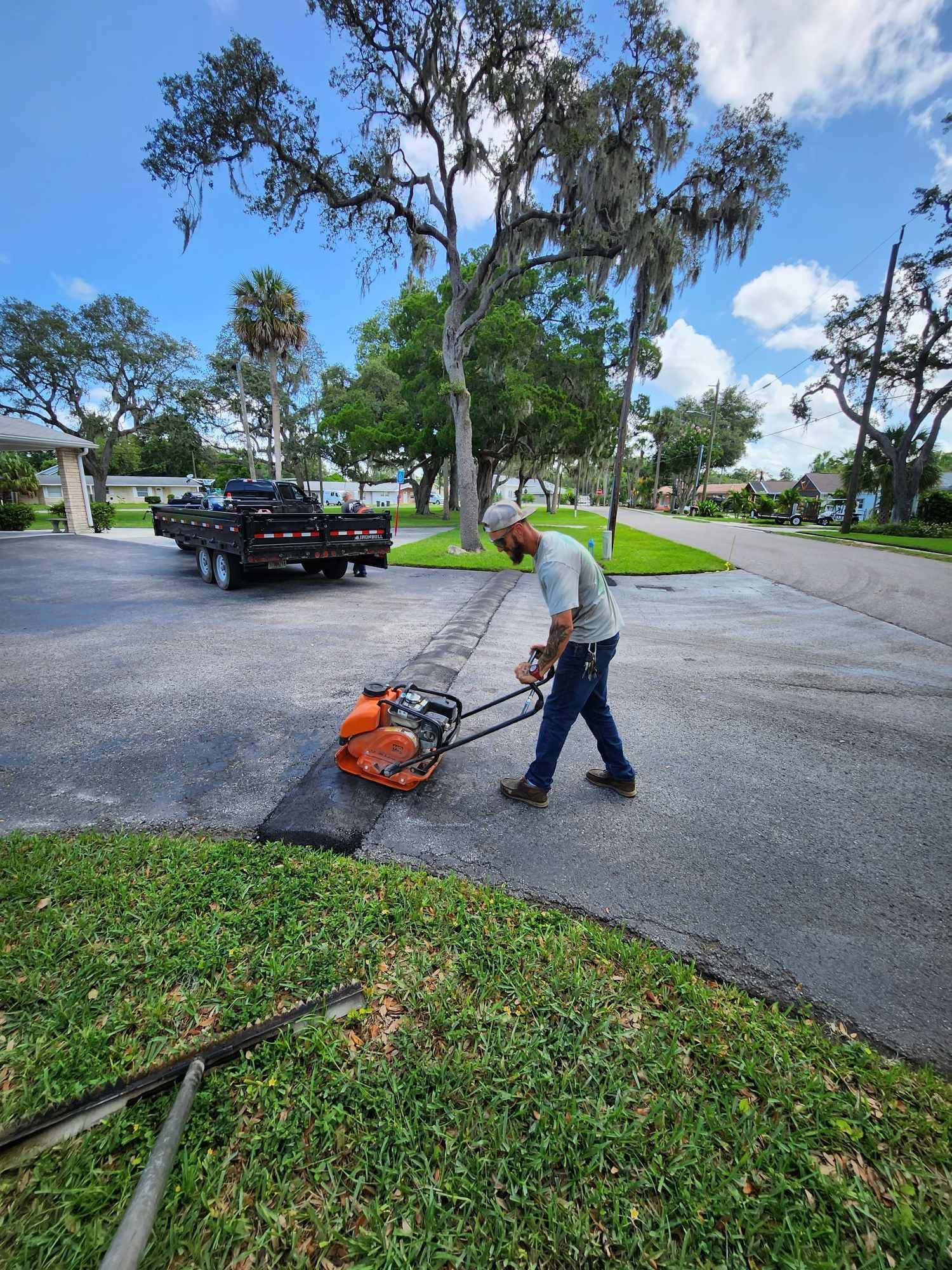 A man is using a lawn mower to cut the grass on the side of the road