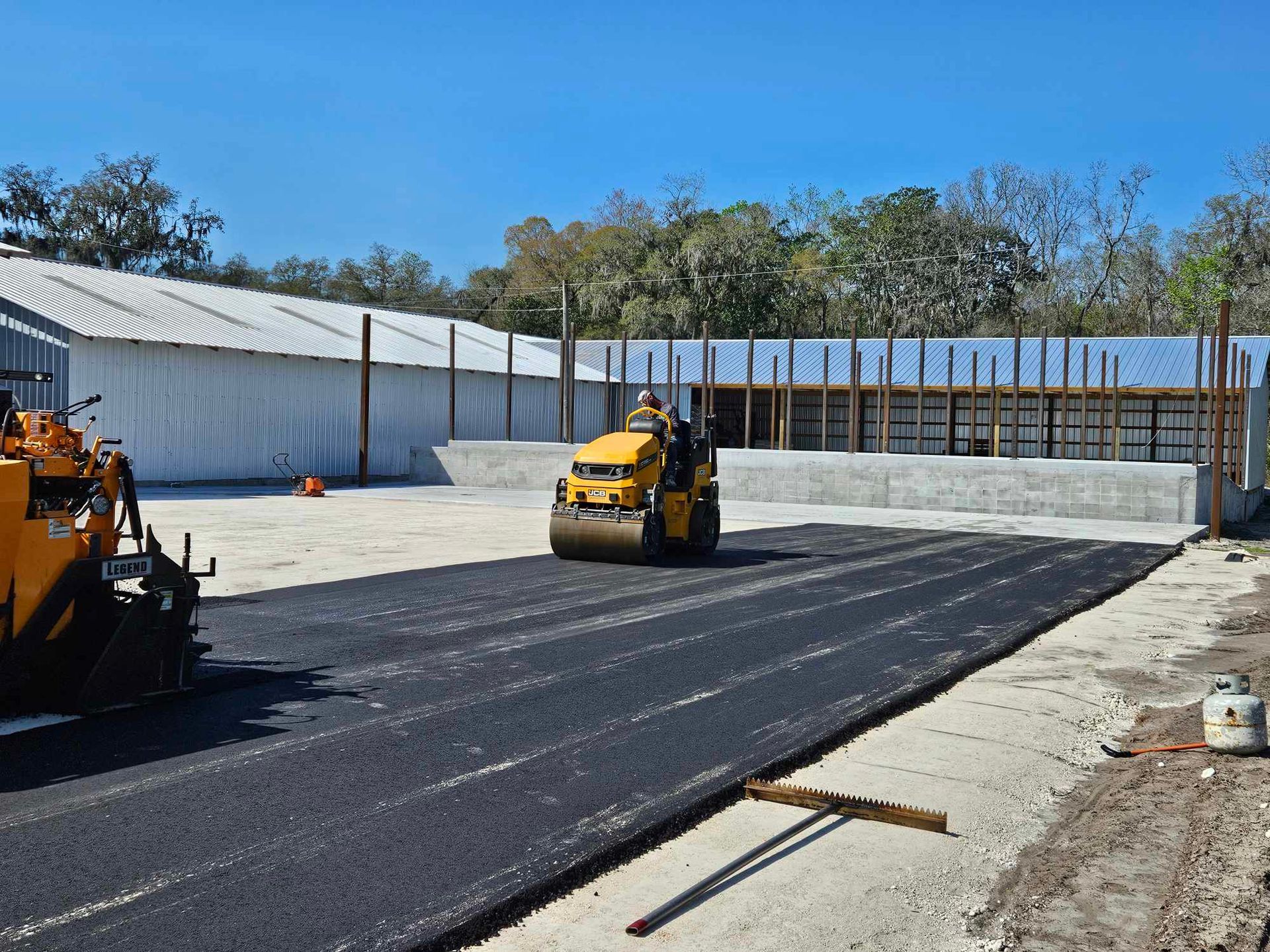 A yellow roller is rolling asphalt on a construction site