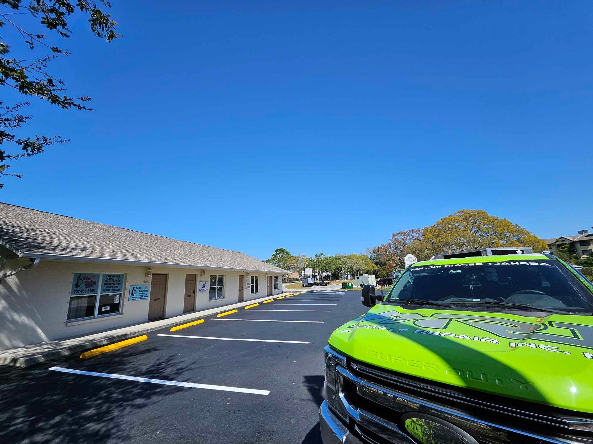 A green truck is parked in a parking lot