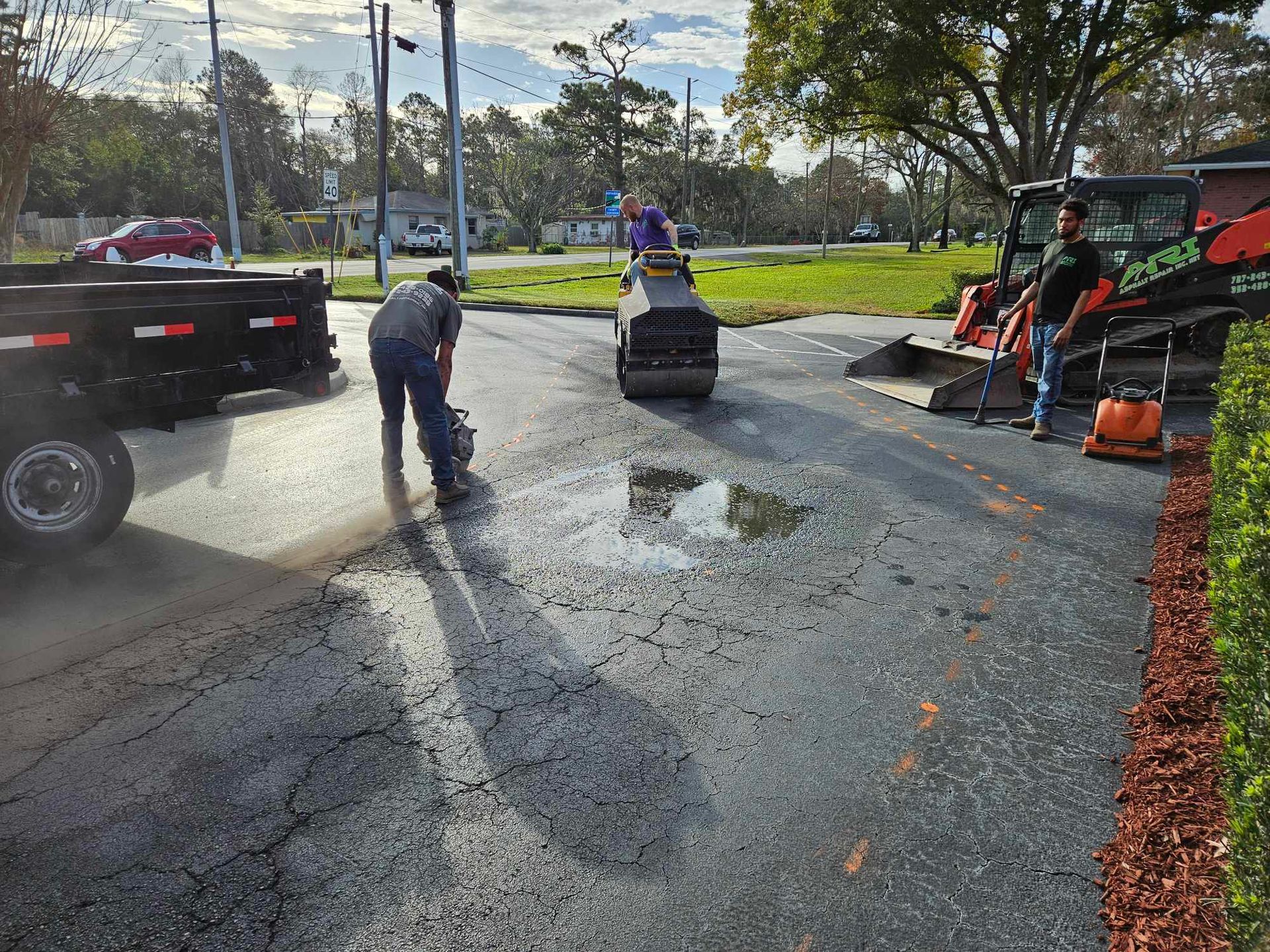 A man is cleaning a puddle of water on the side of the road