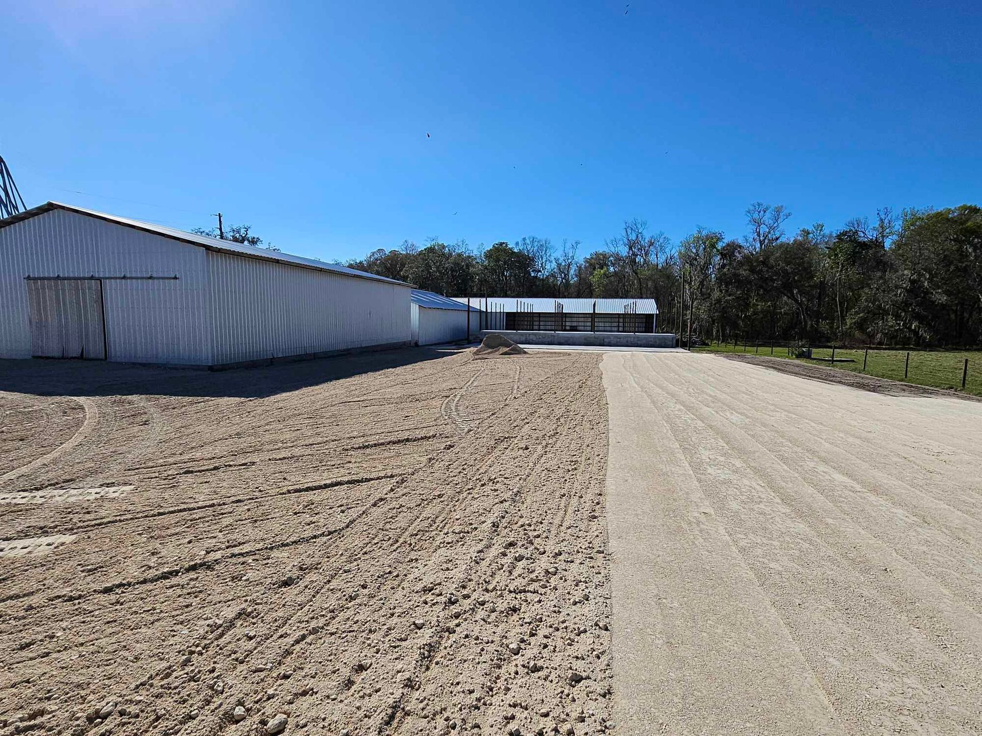 A dirt road leading to a large white building
