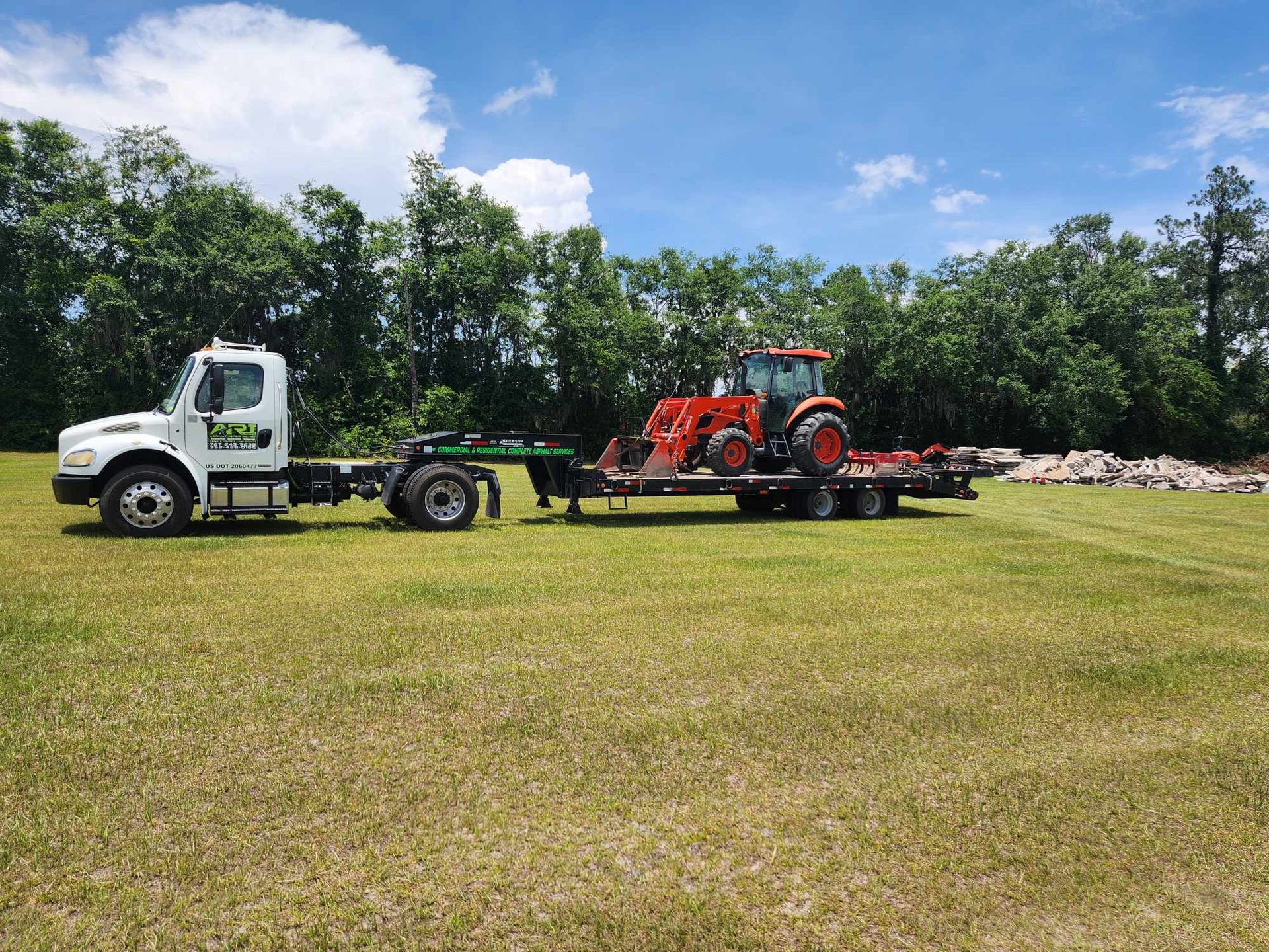 A truck is towing a tractor on a trailer 