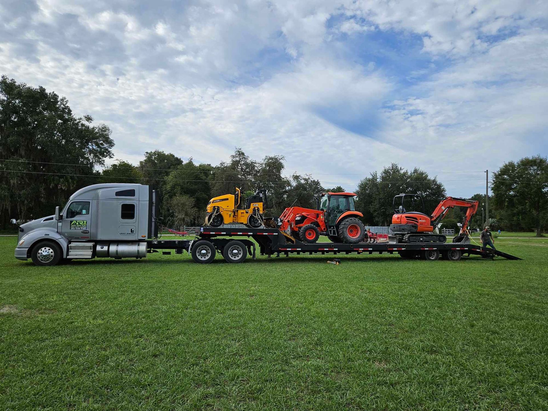 A semi truck is carrying two tractors on a trailer