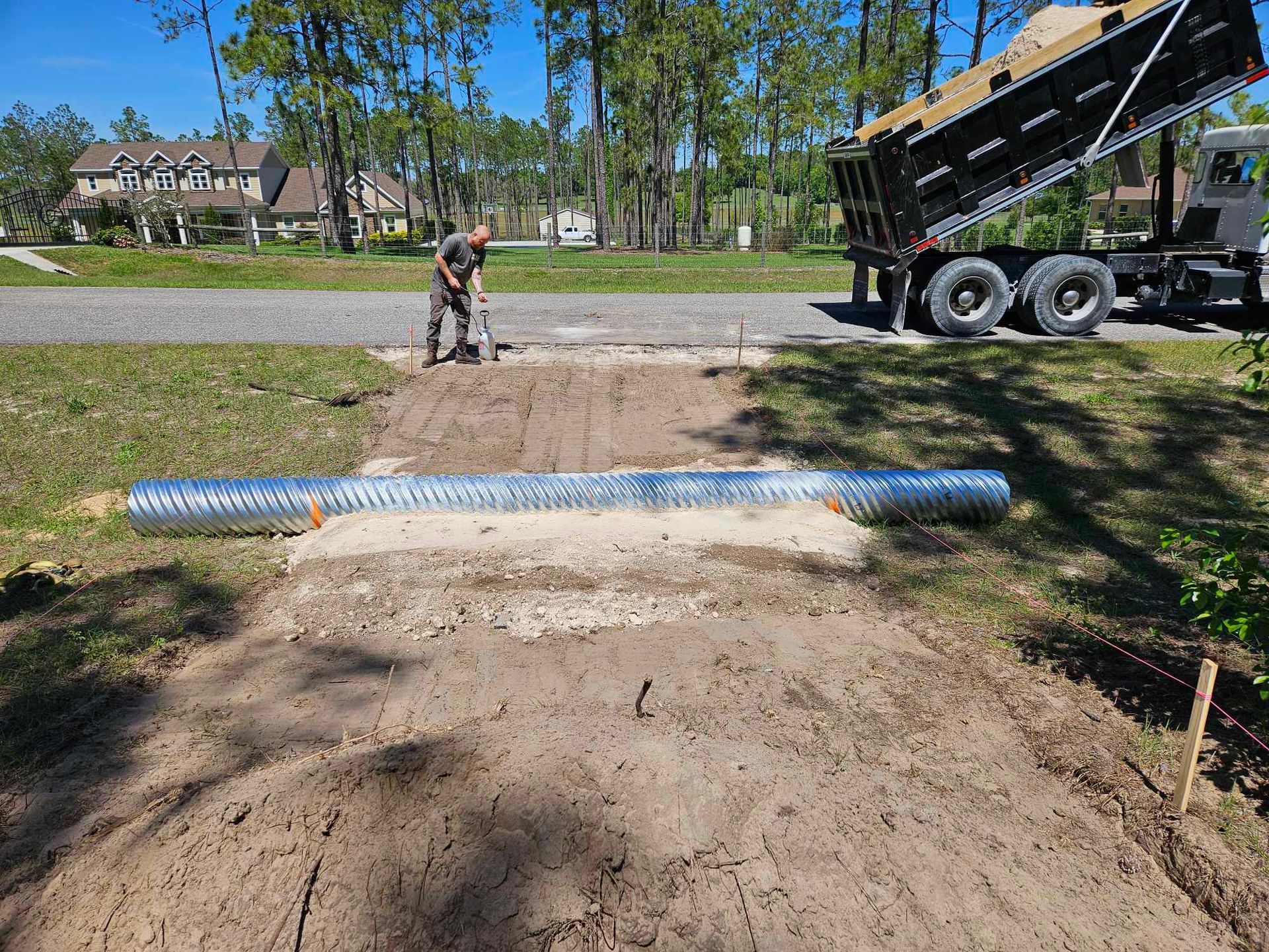 A man is digging in the dirt in front of a dump truck