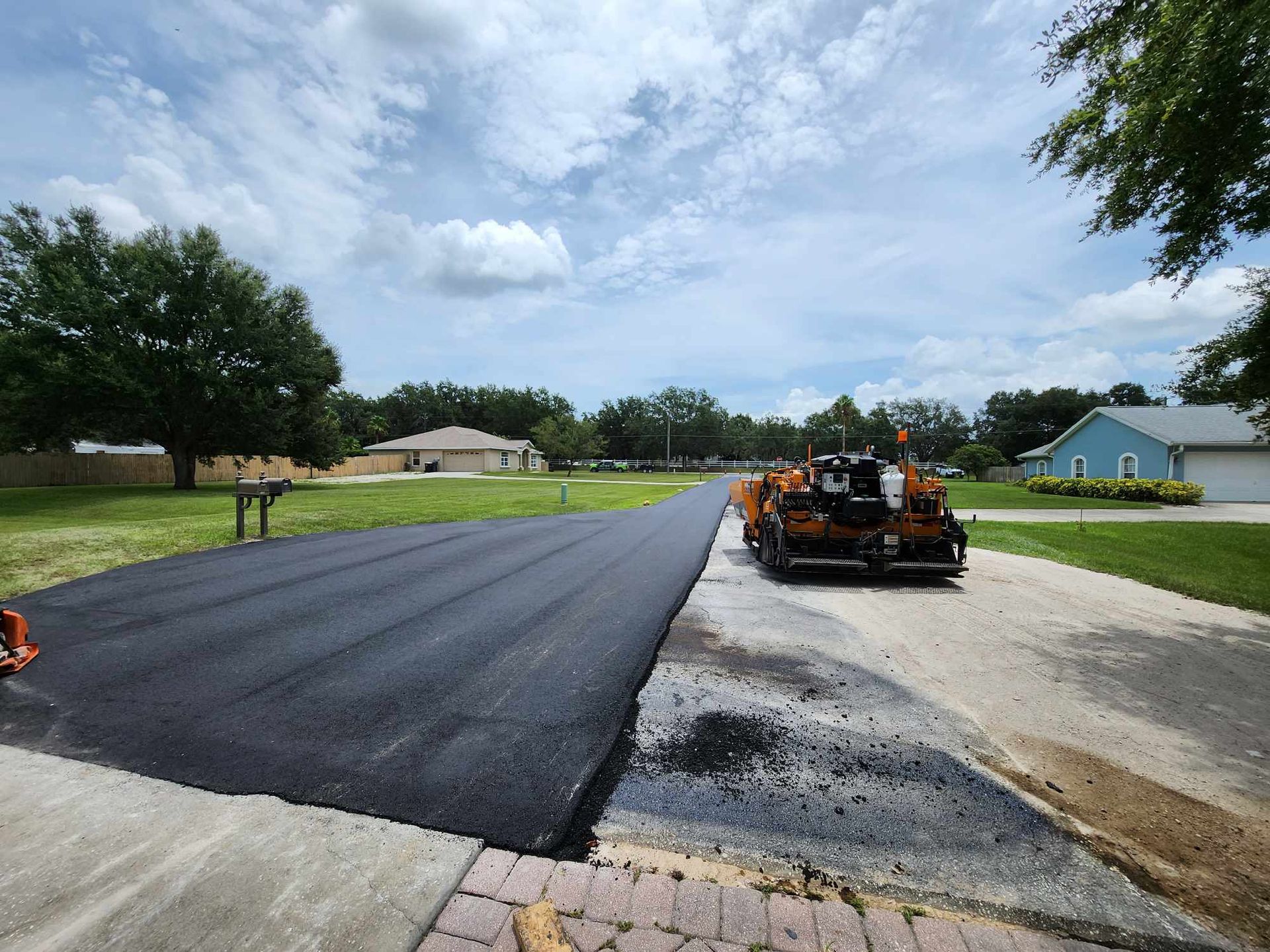 A machine is laying asphalt on the side of a road