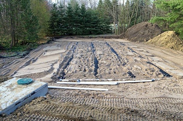 A septic system installation with a buried tank, distribution field, and pipes in a wooded area.