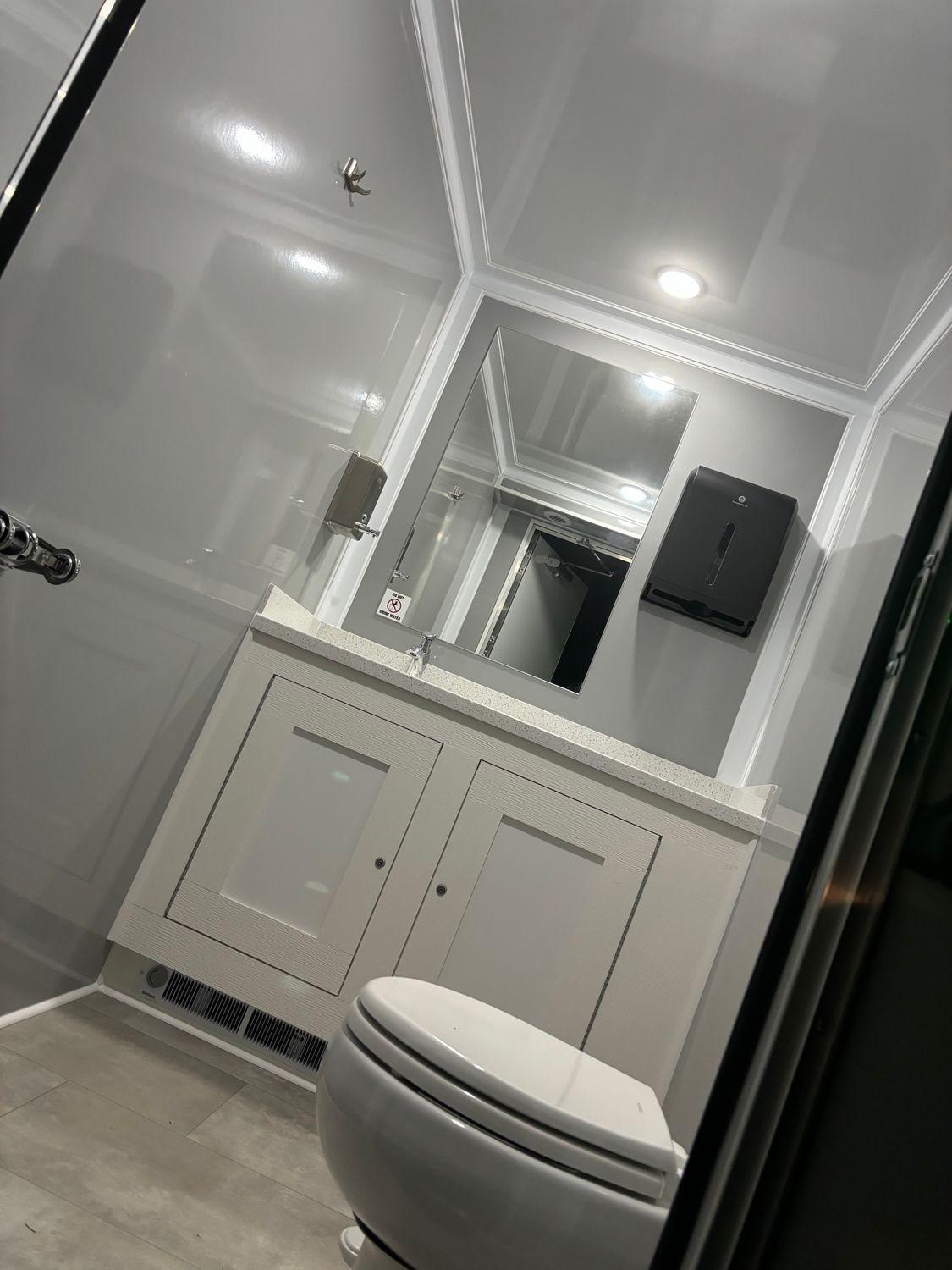 White luxury restroom with toilet, vanity, and mirror.