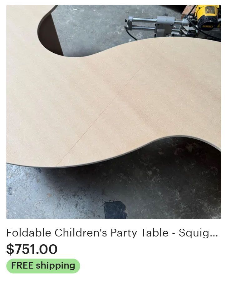 Foldable children's party table with wavy edges, light wood color, on a work surface.
