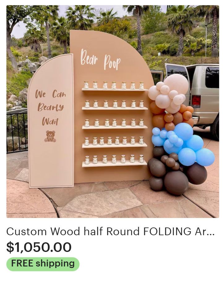 A half-round wood display with small bottles, text, and balloons for an event.