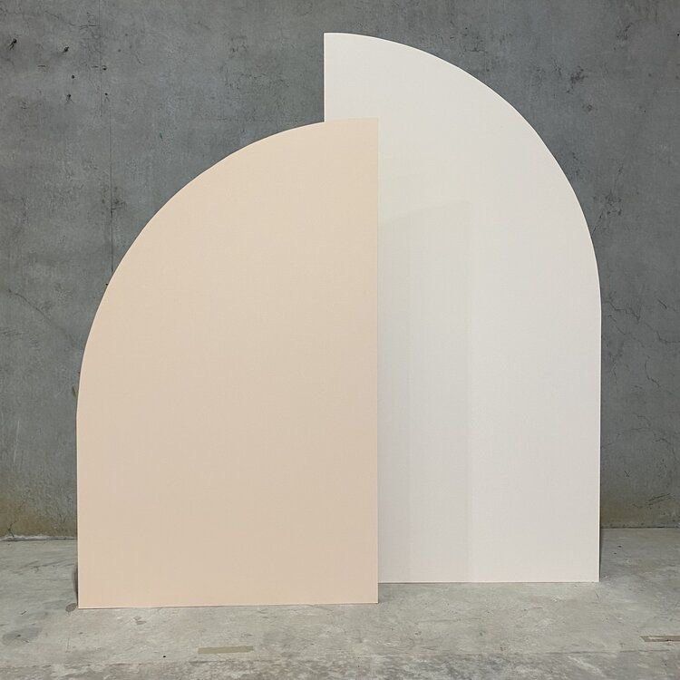 A white and pink arch is sitting on a concrete floor