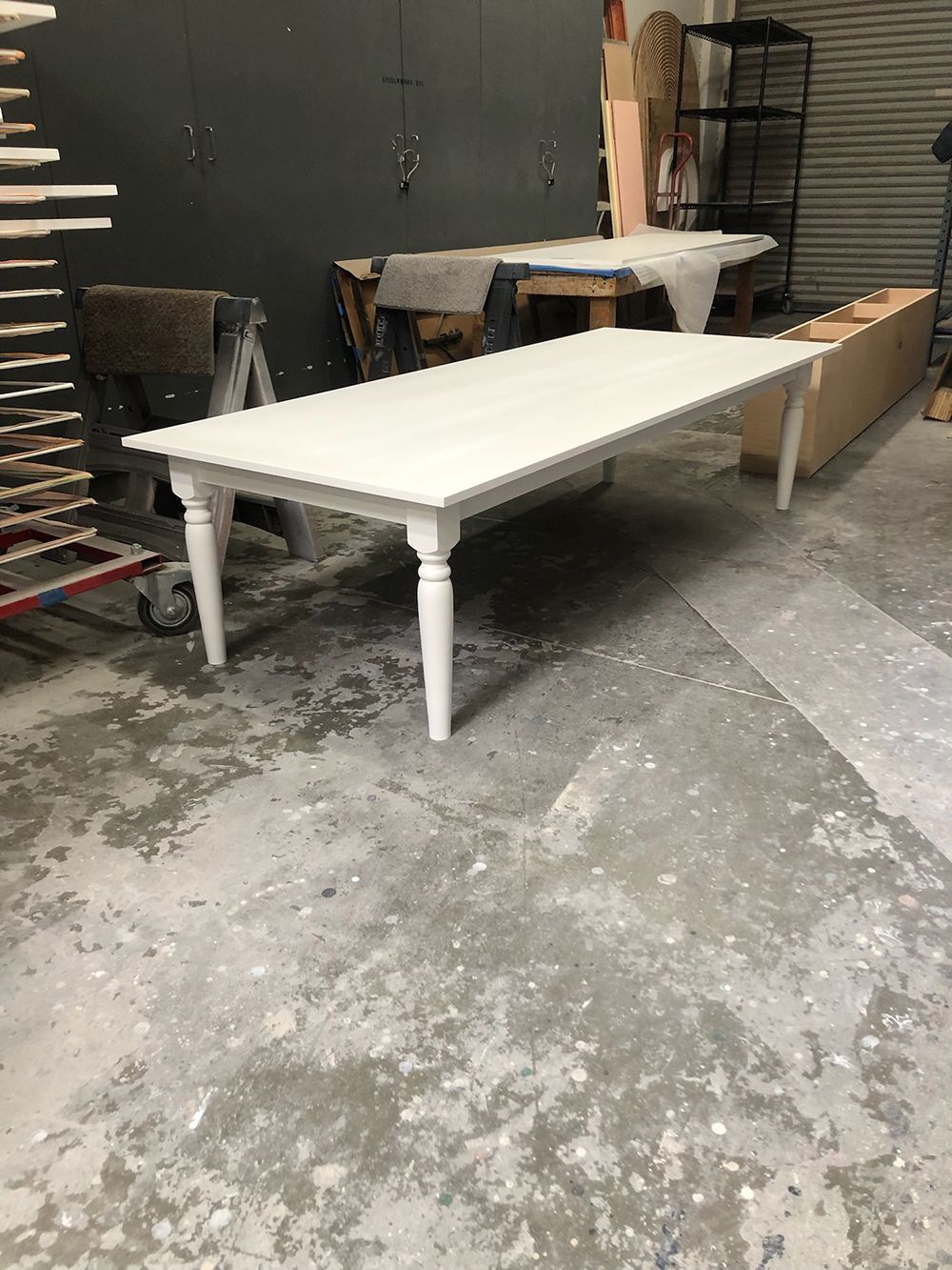 A long white table is sitting on a concrete floor in a room