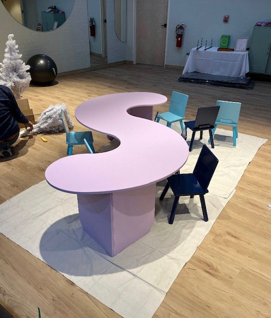 A pink table and chairs in a room with a christmas tree in the background