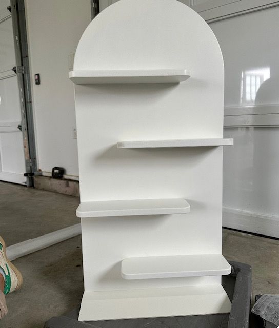 A white shelf with four shelves is sitting in a garage