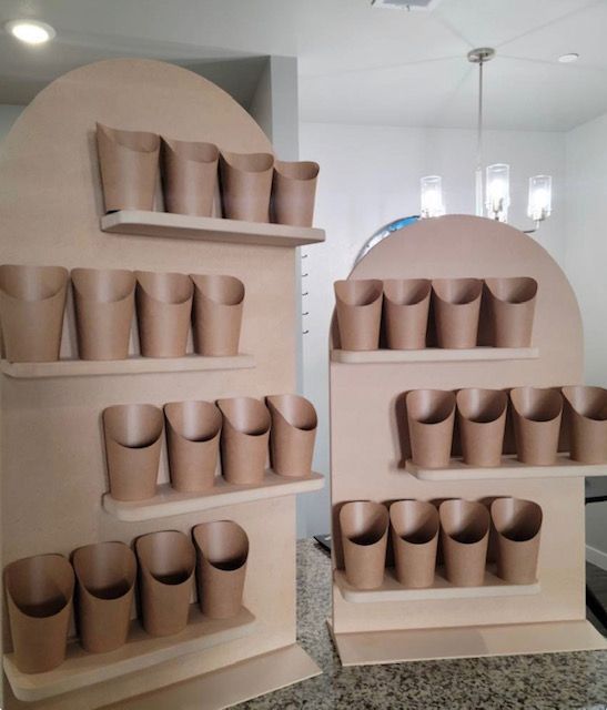 Two shelves filled with brown cups on a counter