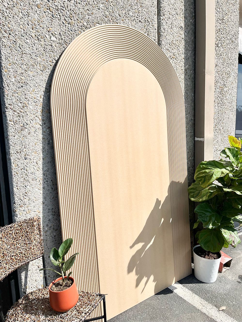 A wooden arch is sitting on a concrete wall next to potted plants