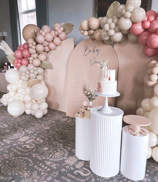 A room filled with balloons and a cake on a stand