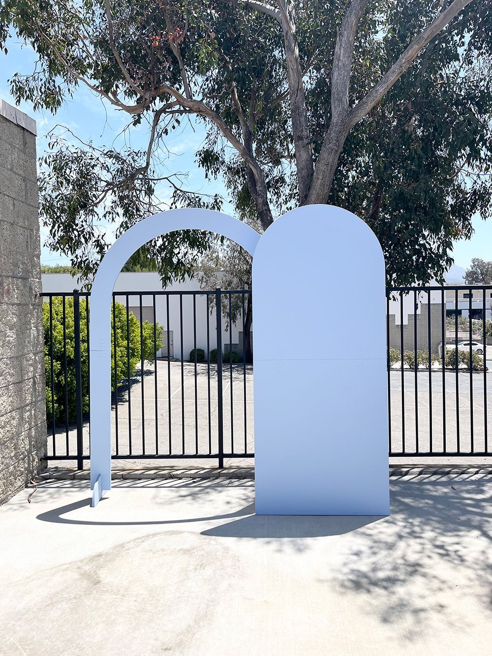 A white archway is sitting in front of a fence