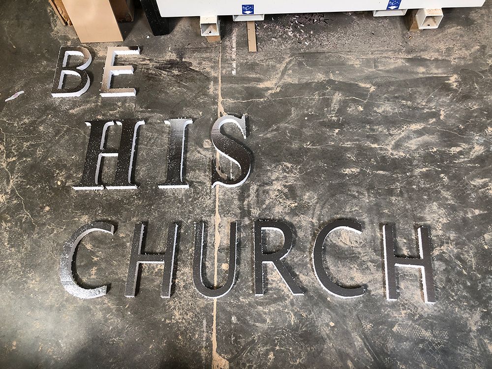 A sign that says be his church is sitting on a concrete floor