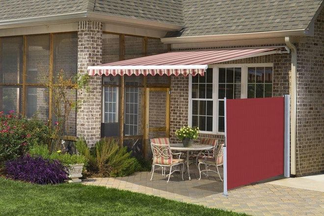 Patio with red and white striped awning and privacy screen; table and chairs set.