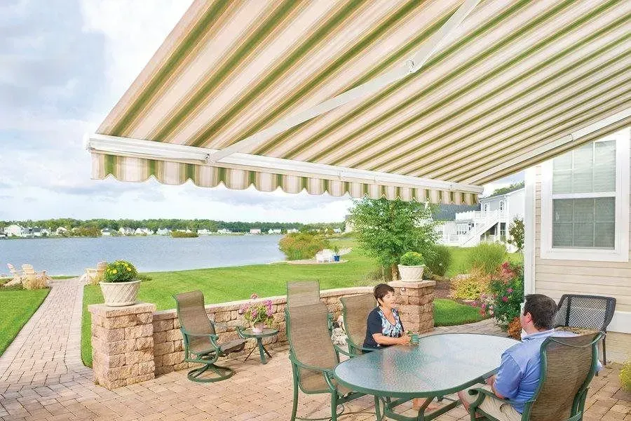 Couple sitting under a striped awning, overlooking a lake.
