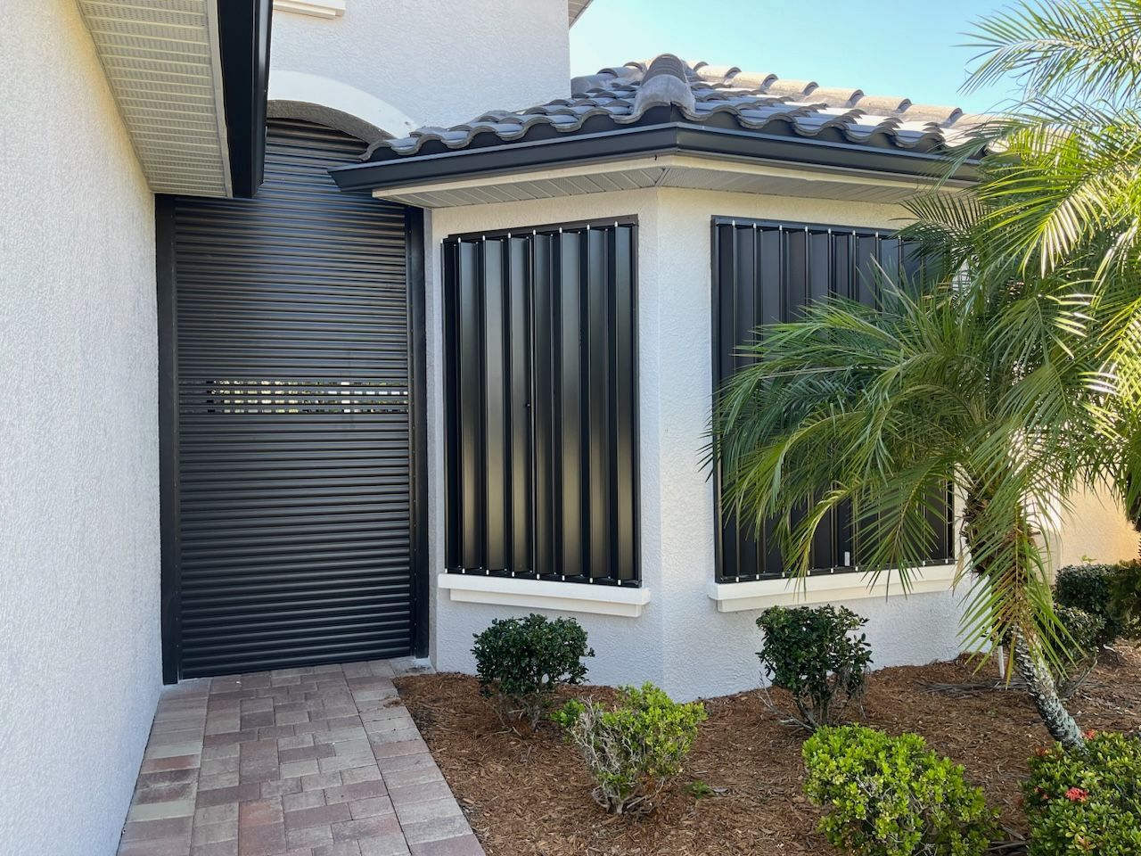 A white house with a black door and shutters on the windows