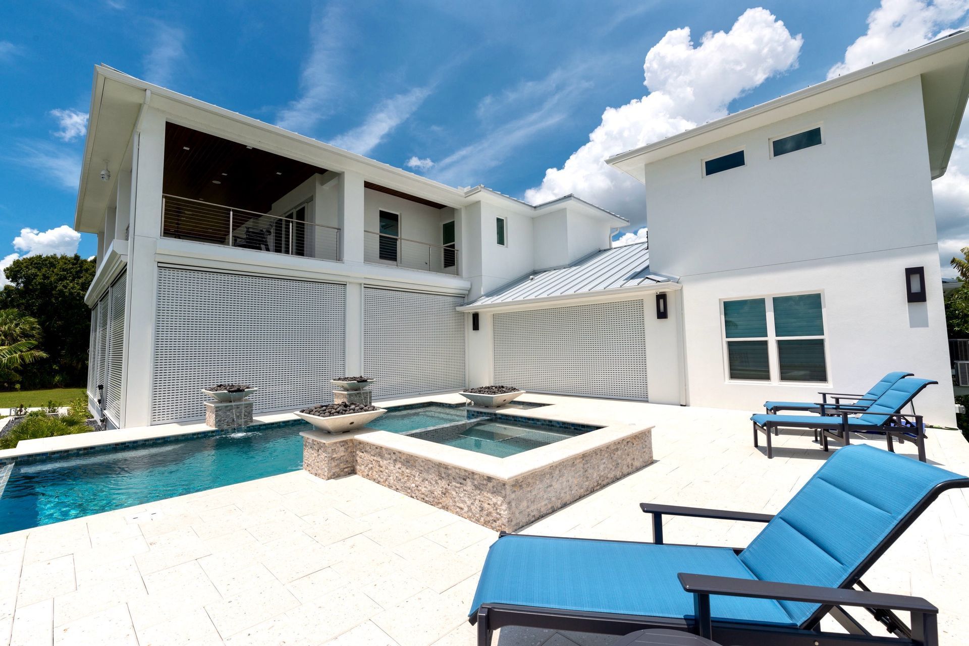 A large white house with a swimming pool and lounge chairs