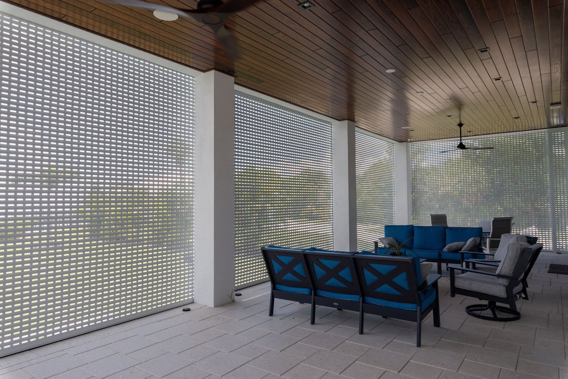 A screened in porch with a blue couch and chairs
