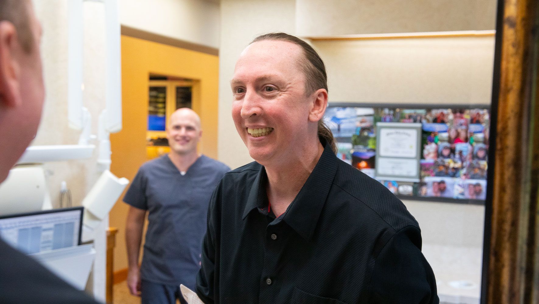 A man is smiling in front of a mirror in a dental office.