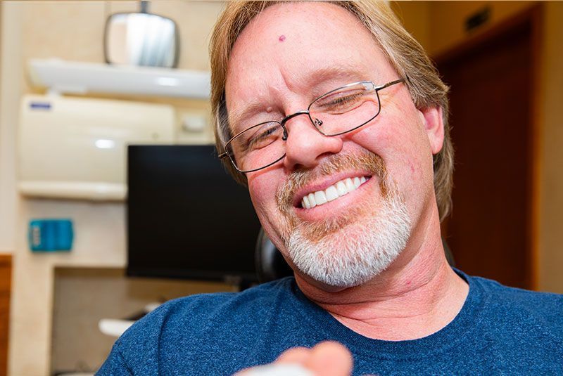 A man with glasses and a beard is smiling at the camera